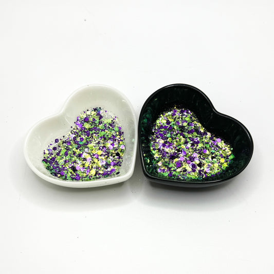 Two heart shaped containers, one black, one white, containing a Green/Purple chunky glitter mix.