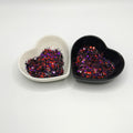 Two heart shaped containers, one black, one white, containing a Black/Red/Purple chunky glitter mix.