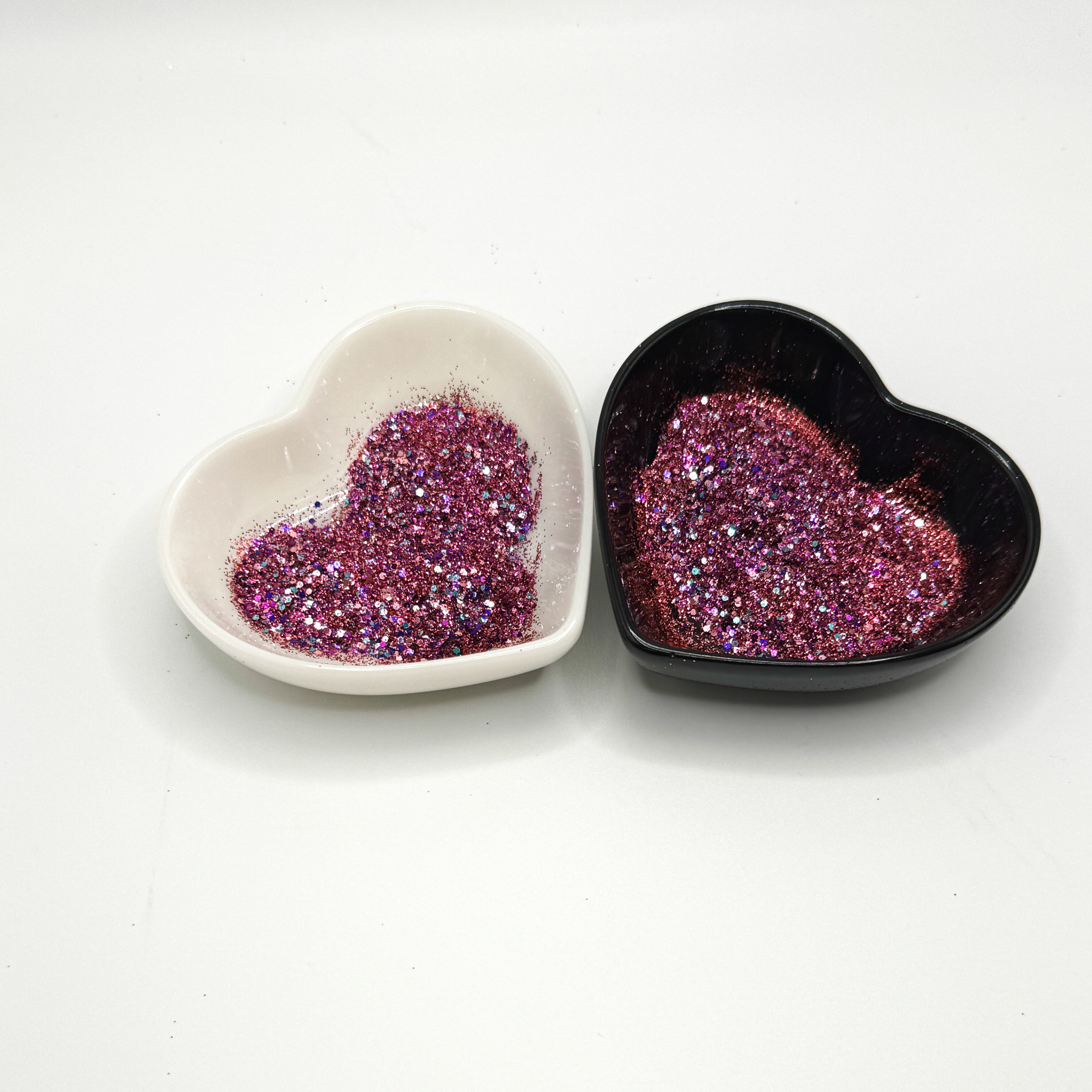 A white and black heart shaped dish showing a Pink/Red/Blue/Purple medium glitter mix.