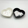 Two heart shaped containers, one black, one white, containing a White/Red/Green chunky glitter mix.