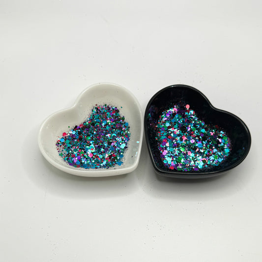 Two heart shaped containers, one black, one white, containing a Green/Black/Purple/Pink/Teal/Blue chunky glitter mix.