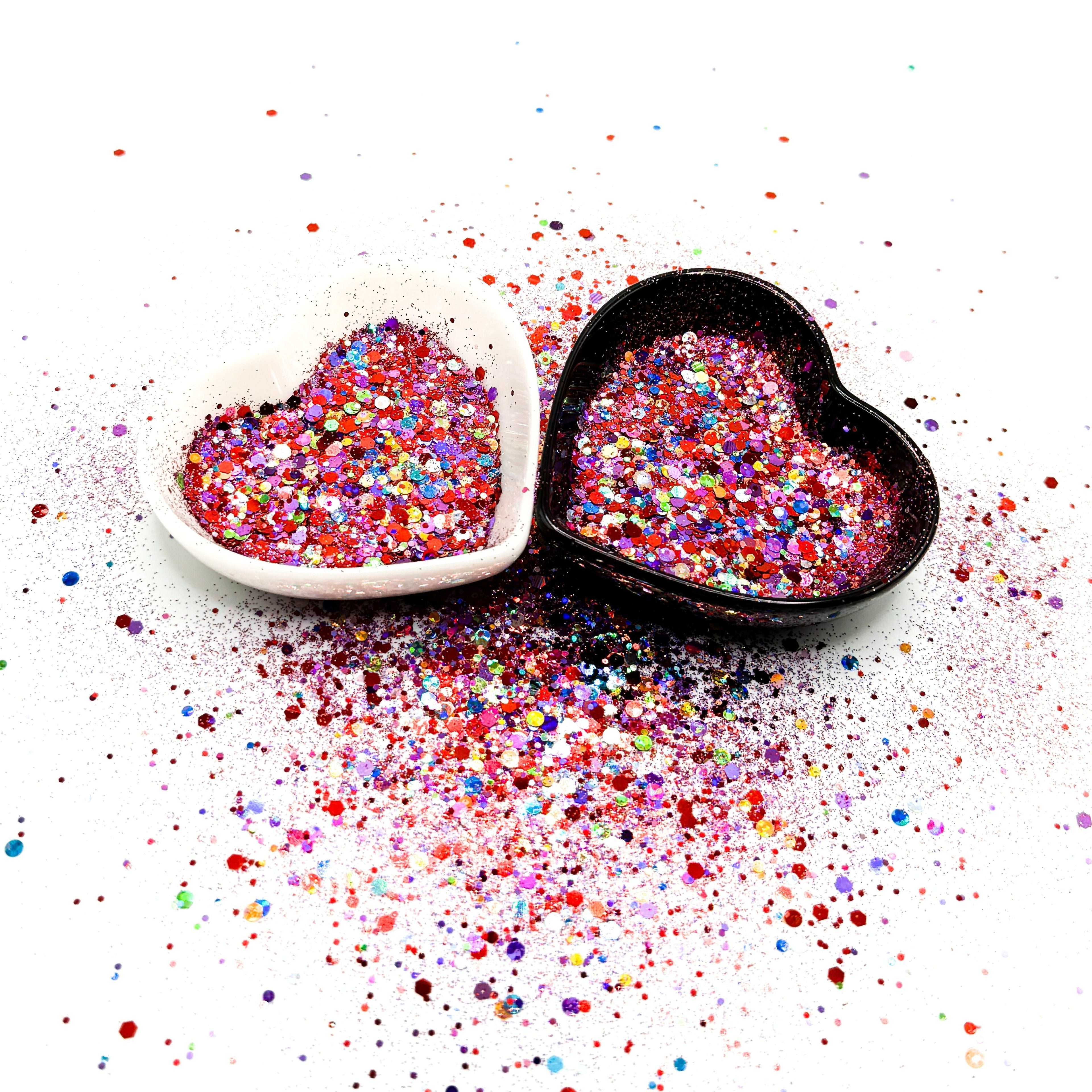 Two heart shaped containers, one black, one white, containing a Red/Purple/Rainbow chunky glitter mix.