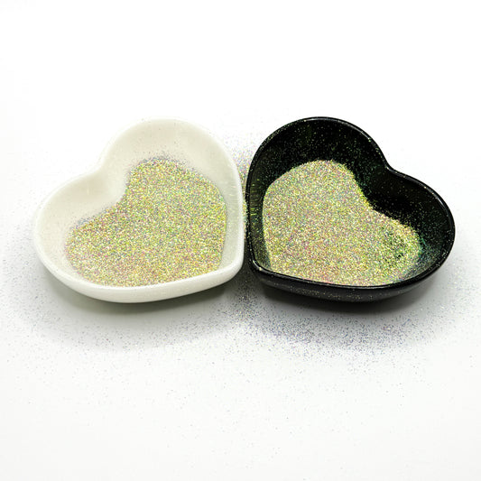 Two heart-shaped dishes, one white and one black, filled with extra fine multicolored glitter.
