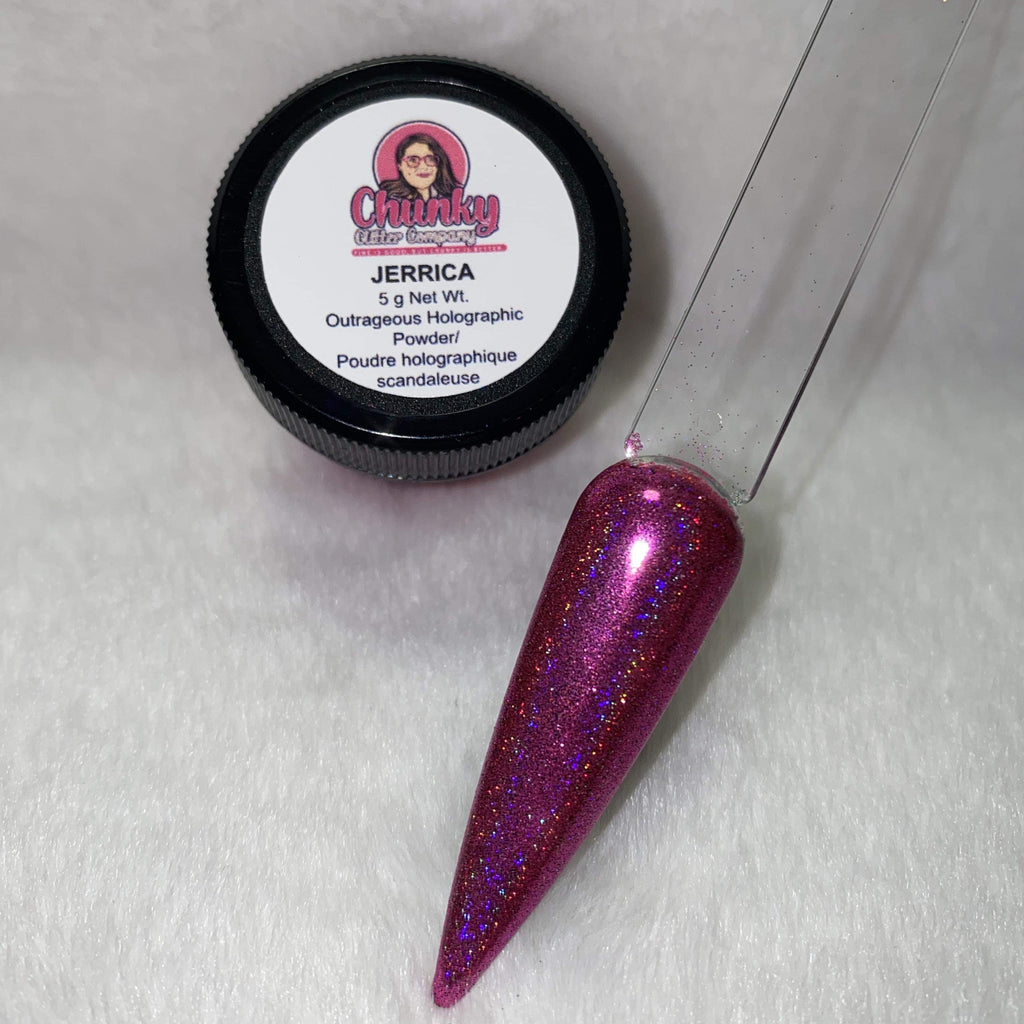 A small jar of pink holographic glitter powder next to a sample application on a clear nail.