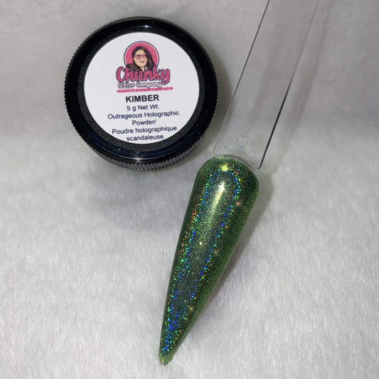 A small jar of green holographic glitter powder next to a sample application on a clear nail.