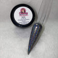 A small jar of silver holographic glitter powder next to a sample application on a clear nail.