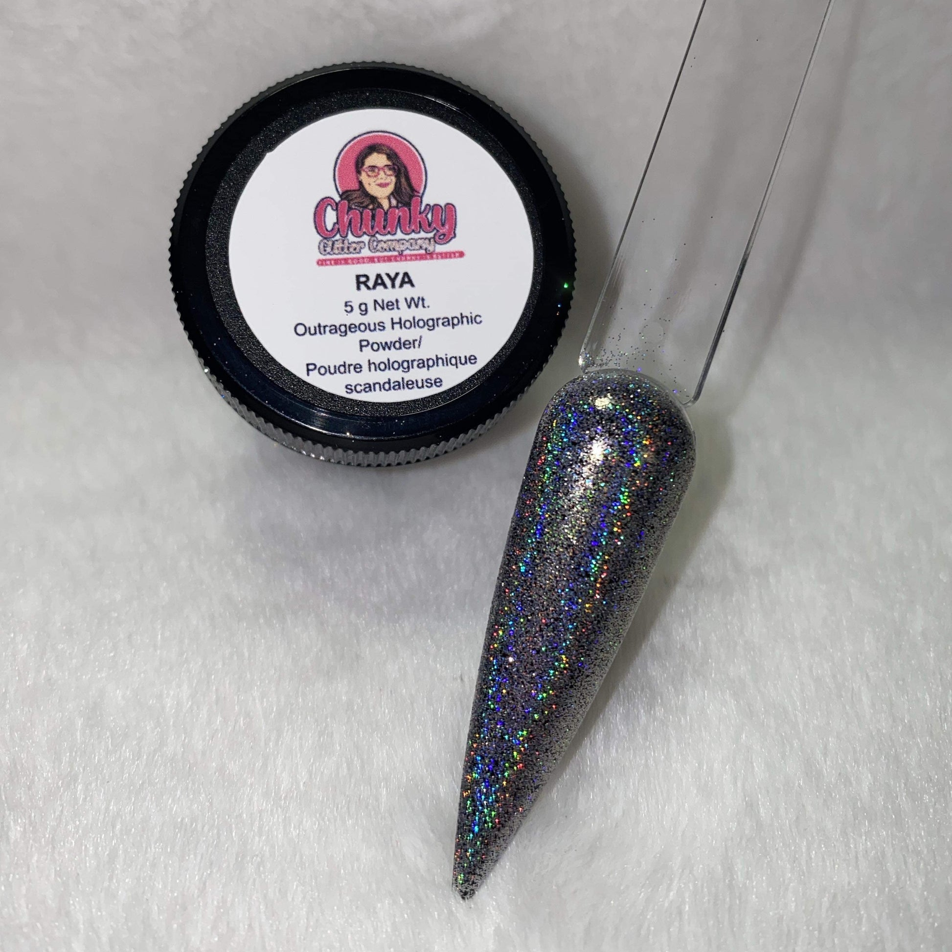 A small jar of silver holographic glitter powder next to a sample application on a clear nail.
