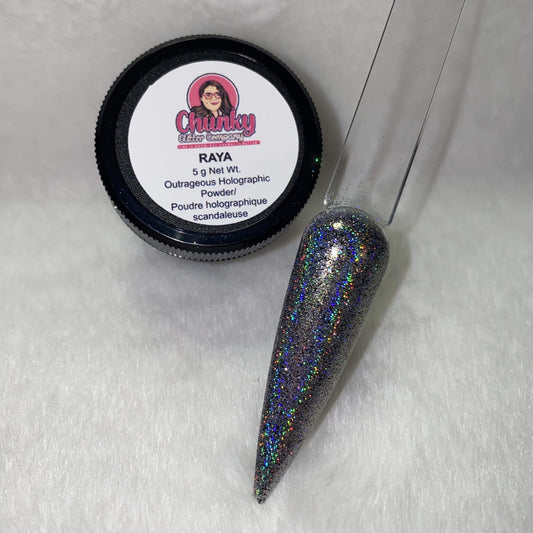 A small jar of silver holographic glitter powder next to a sample application on a clear nail.