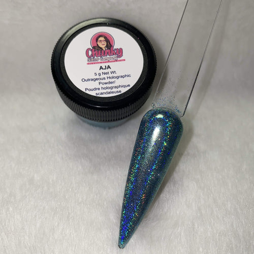 A small jar of blue holographic glitter powder next to a sample application on a clear nail.
