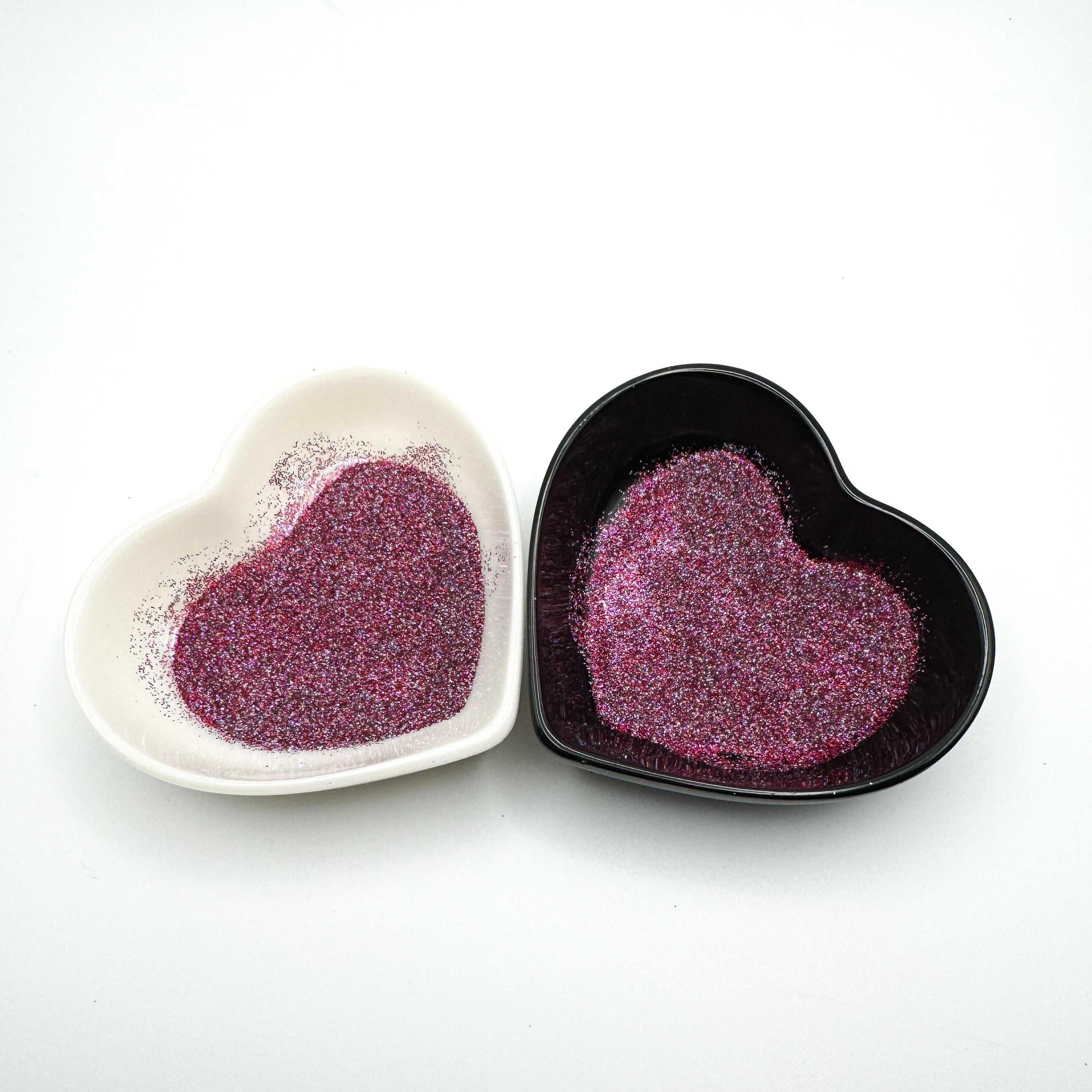 Two heart-shaped dishes containing extra fine purple glitter, displayed on a white background.