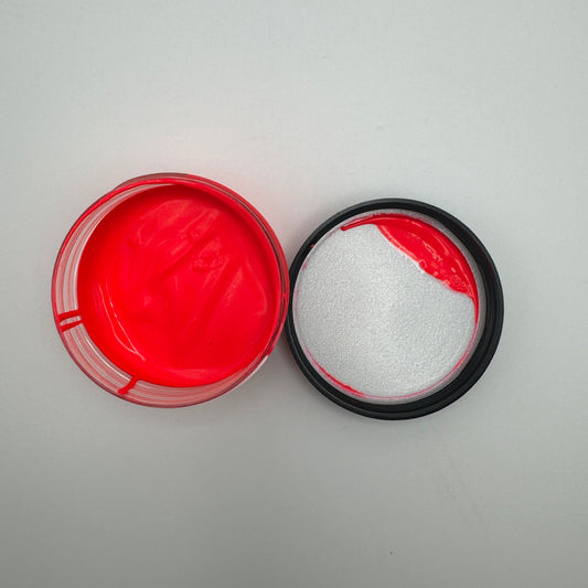 A jar of electric pink pigment paste, with the lid partially opened, revealing the vibrant pink color inside.