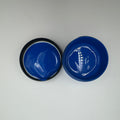 Two small open jars with blue pigment paste, viewed from above on a white background.