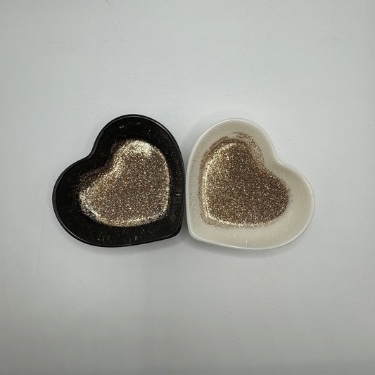 Two heart-shaped containers of glitter, one black and the other white, both showing an extra fine, gold glitter mix