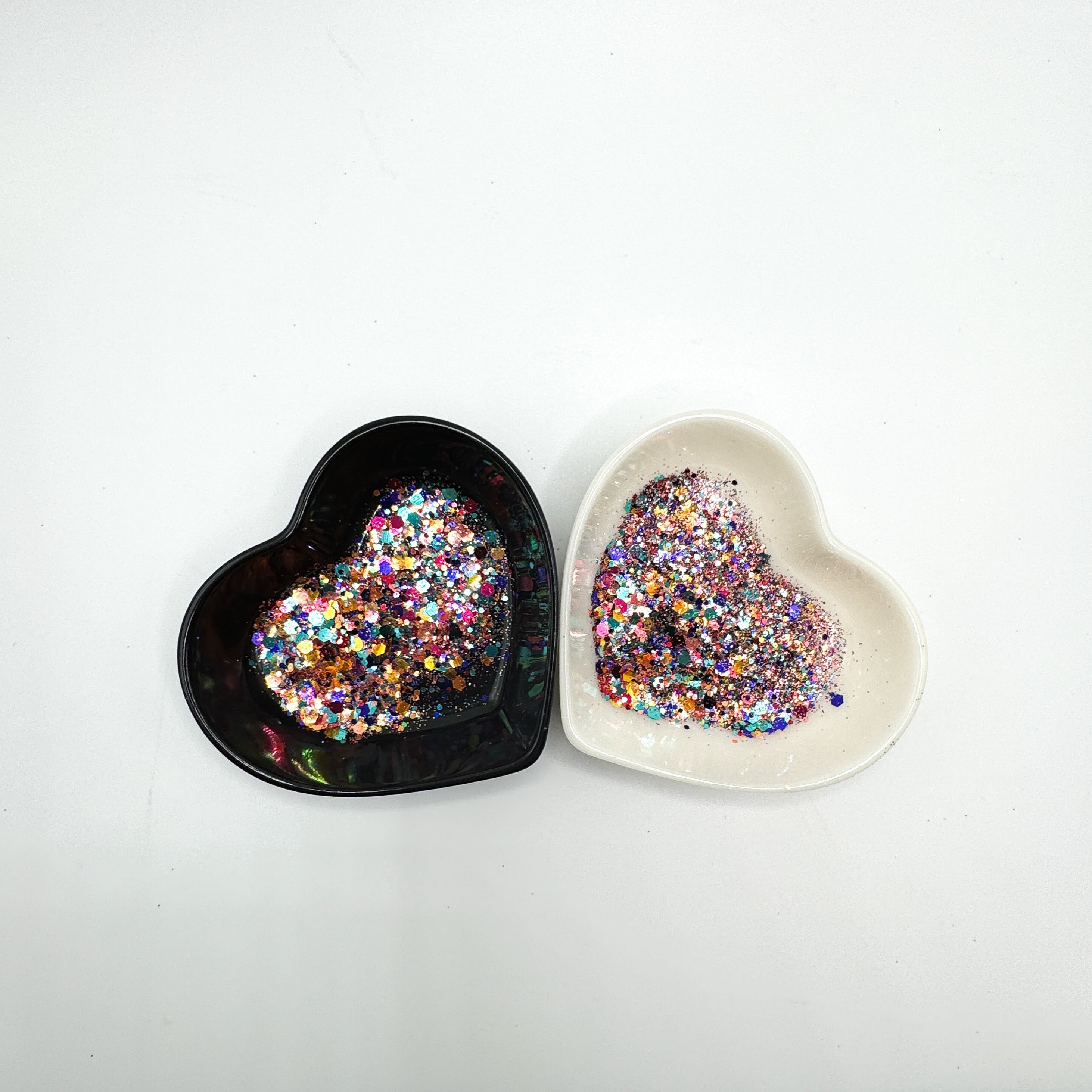 Two heart shaped containers, one black, one white, containing a Pink/Light Teal/Orange/Coral/Indigo chunky glitter mix.