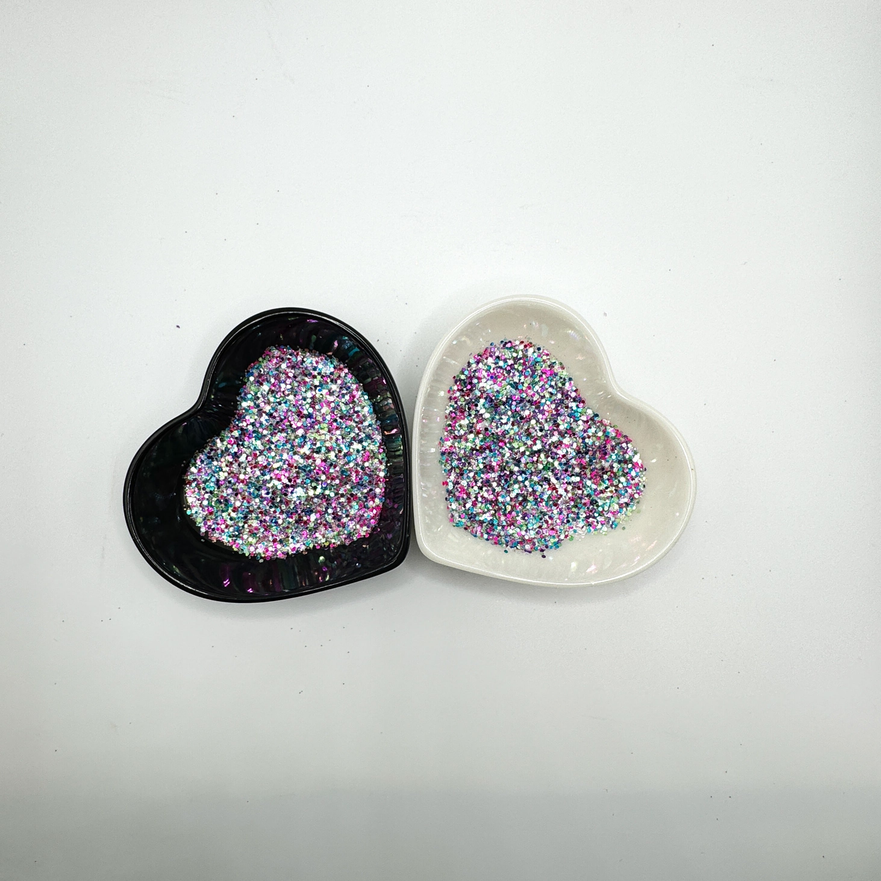 A white and black heart shaped dish showing a White/Rainbow/Pink/Purple/Green medium glitter mix.