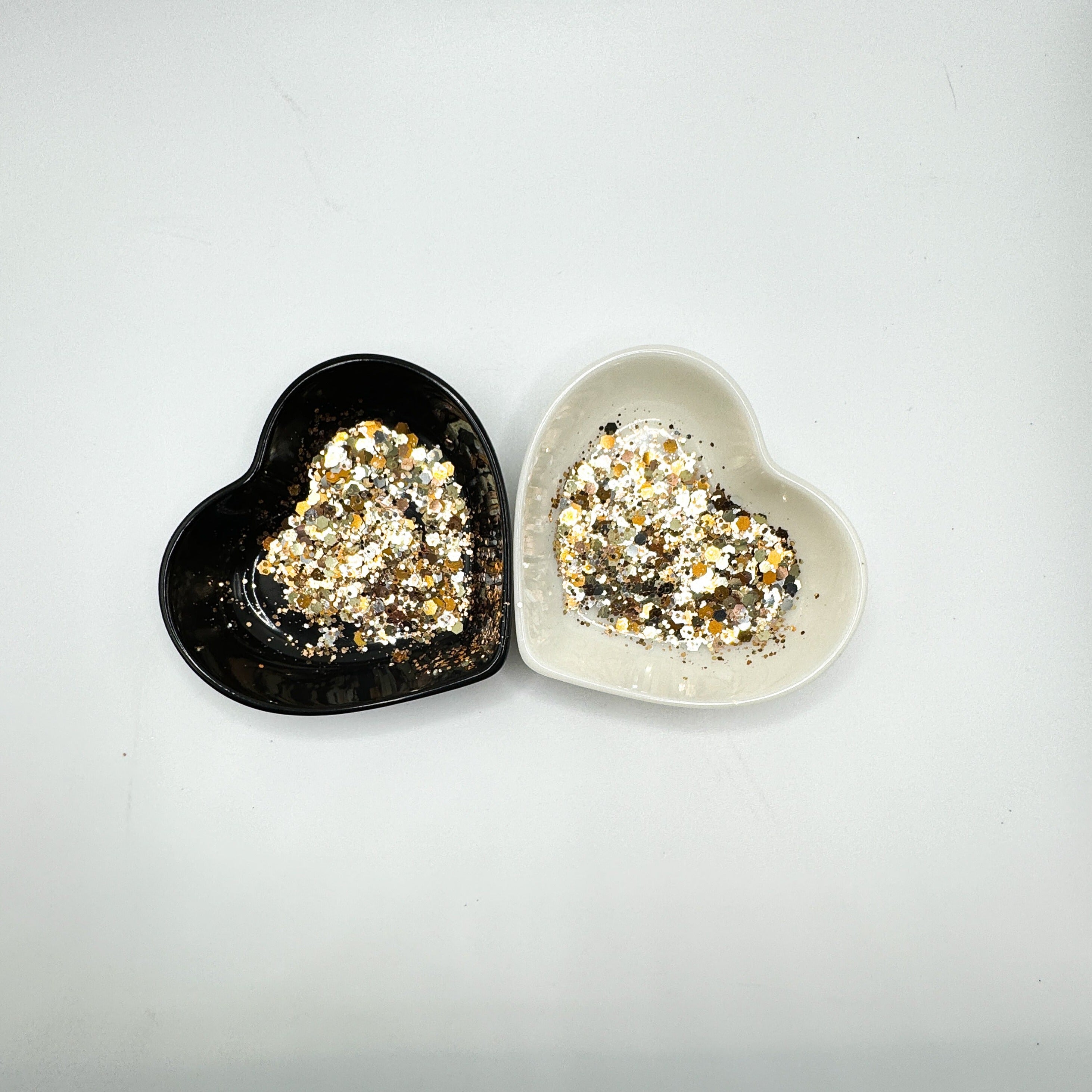 Two heart shaped containers, one black, one white, containing a Bronze/Gold/Silver/Rose Gold chunky glitter mix.