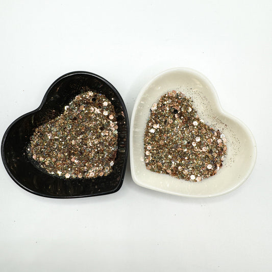 Two heart shaped containers, one black, one white, containing a Light Teal/Black/Silver/Rose Gold chunky glitter mix.