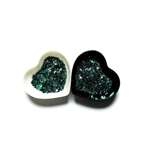 Two heart shaped containers, one black, one white, containing a Teal/Black/White chunky glitter mix.
