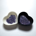 Two heart-shaped containers of glitter, one black and the other white, both showing an extra fine, blue, silver glitter mix.