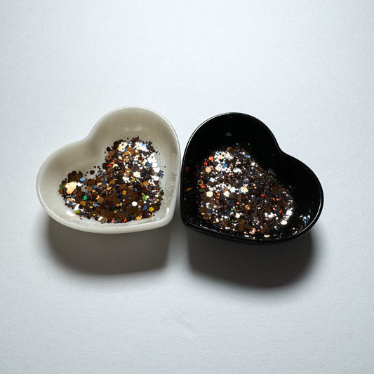 Two heart shaped containers, one black, one white, containing a Blue/Brown/Bronze chunky glitter mix.