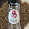 A clear plastic shaker bottle labeled 'Dalton' containing extra fine gold glitter, with a pile of glitter scattered in the background.