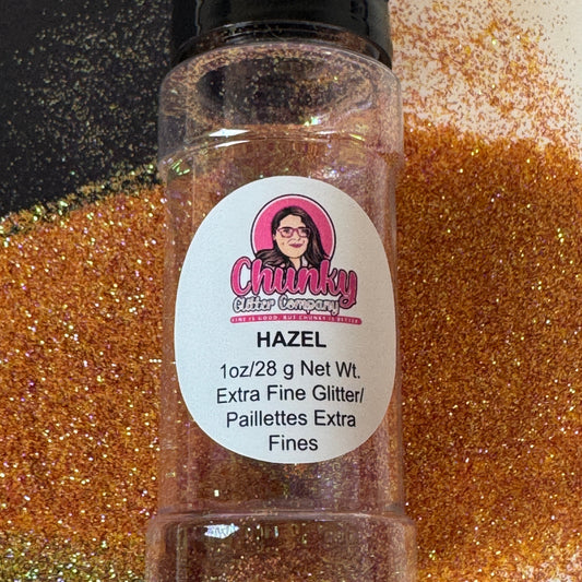 A clear plastic bottle with a black lid, labeled 'Chunky Glitter Company', containing extra fine glitter orange glitter mix with a scattered glitter background.