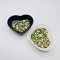 Two heart shaped containers, one black, one white, containing a Red/Green/White/Silver/Gold chunky glitter mix with hexagons and Snowflakes.