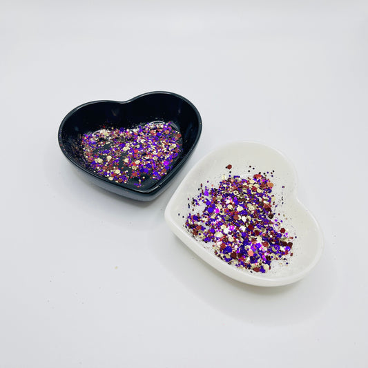 Two heart shaped containers, one black, one white, containing a Purple/Gold/Brown chunky glitter mix.