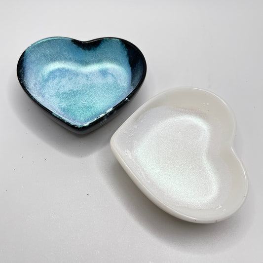 Two heart shaped containers, one black, one white, containing a white chameleon mica powder.