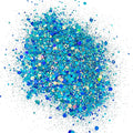 A pile of blue and turquoise colored chunky glitter, spread out on a surface.