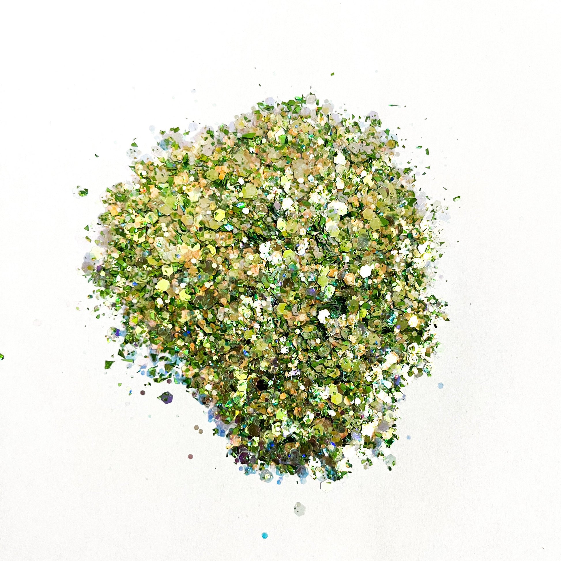 A pile of mixed colours of chunky glitter, including white/green on a white background.