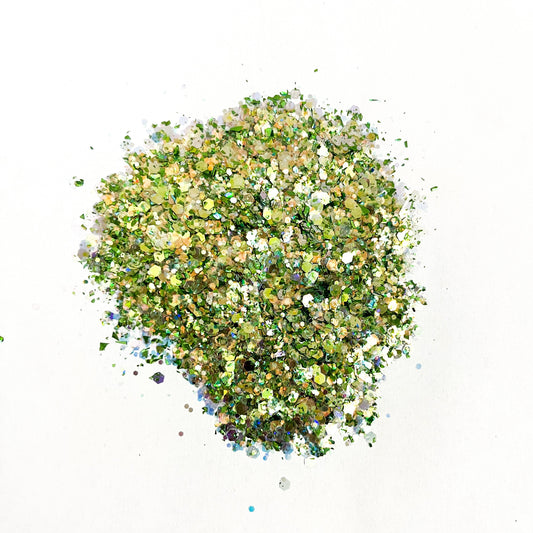 A pile of mixed colours of chunky glitter, including white/green on a white background.