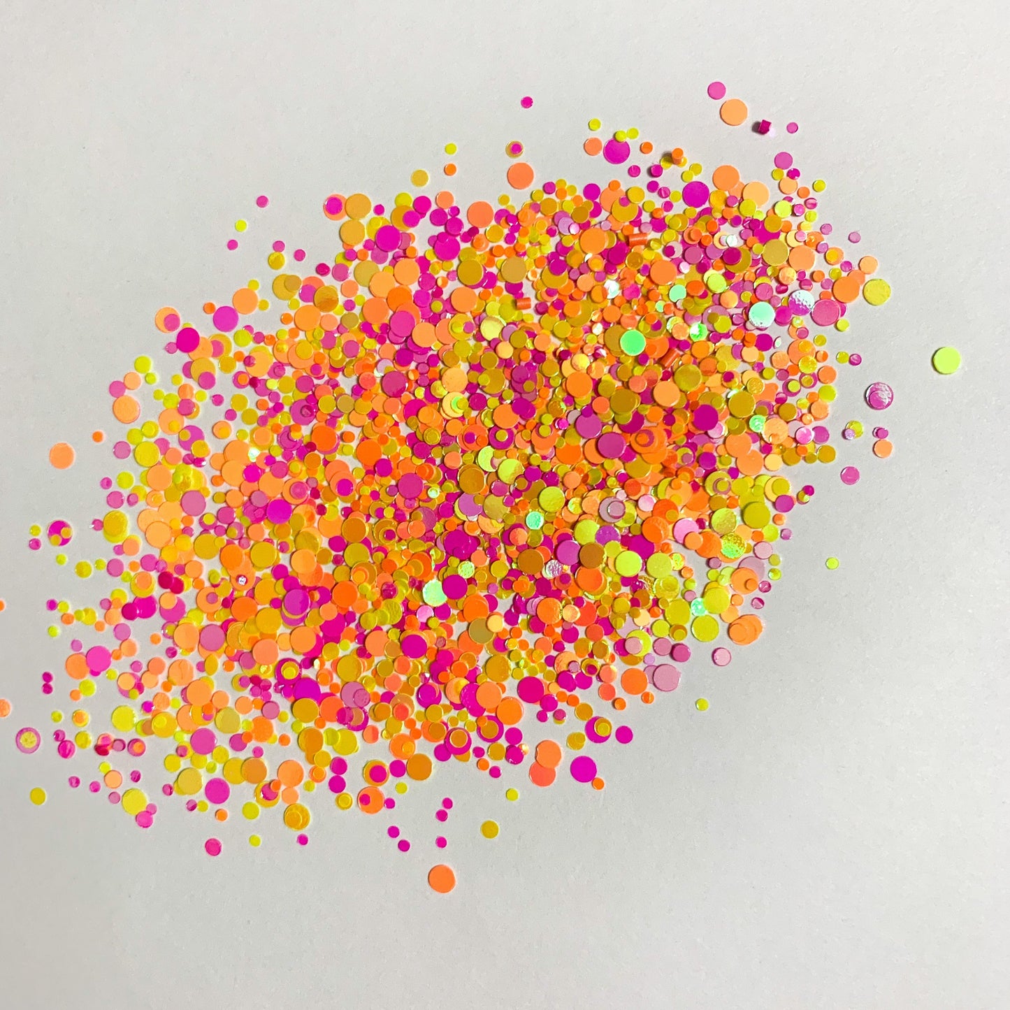 A colorful mix of chunky glitter in orange, pink, yellow, and other colors spread on a white background.