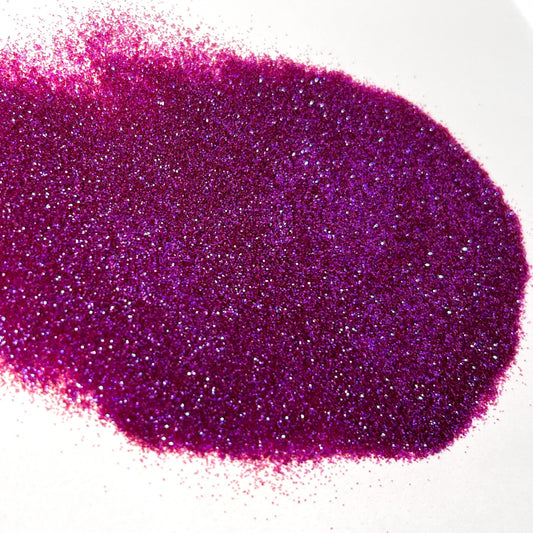 A pile of purple iridescent polyester glitter spread out on a white background.
