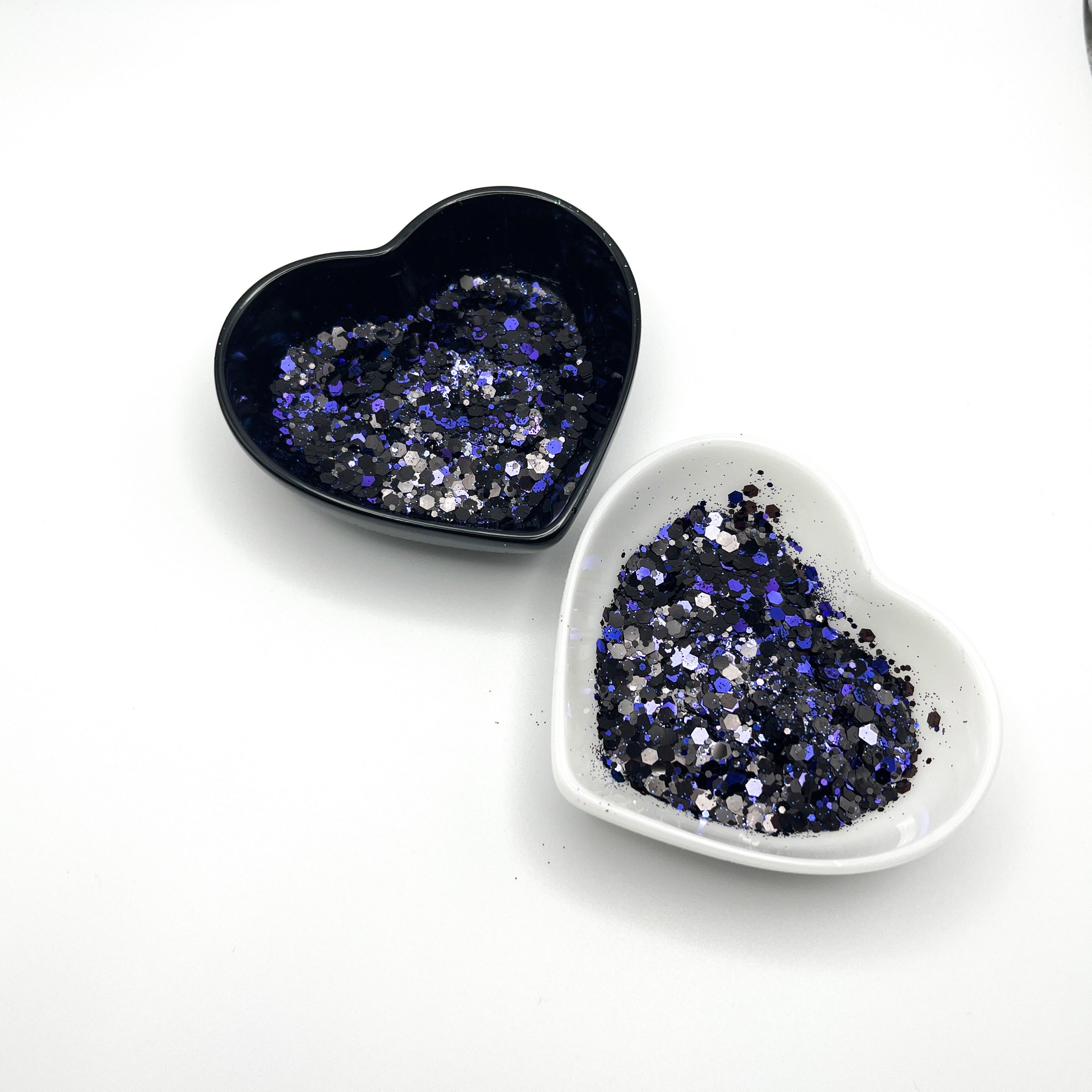 Two heart shaped containers, one black, one white, containing a Black/Blue chunky glitter mix.