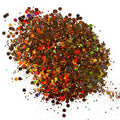 A pile of multicolored chunky glitter, ranging from brown to vibrant hues, spread out on a surface.