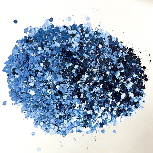 A pile of denim blue chunky glitter on a white background.