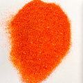 A pile of orange, extra fine glitter spread on a white surface.