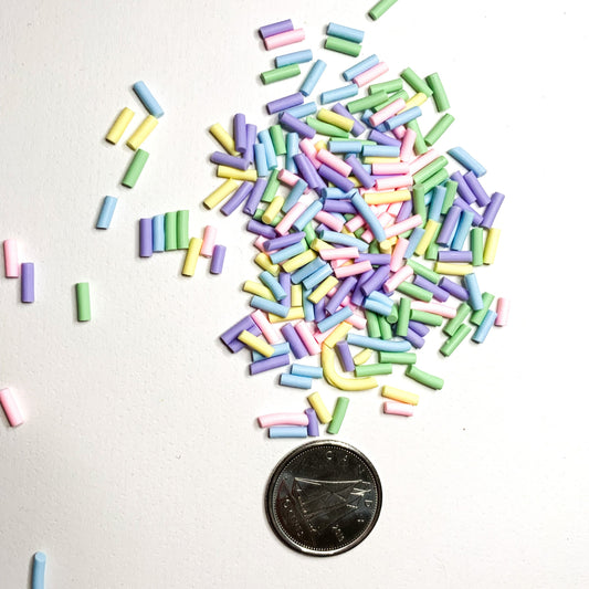 pastel sprinkle polymer clay on a white background with a dime used to show size reference. 