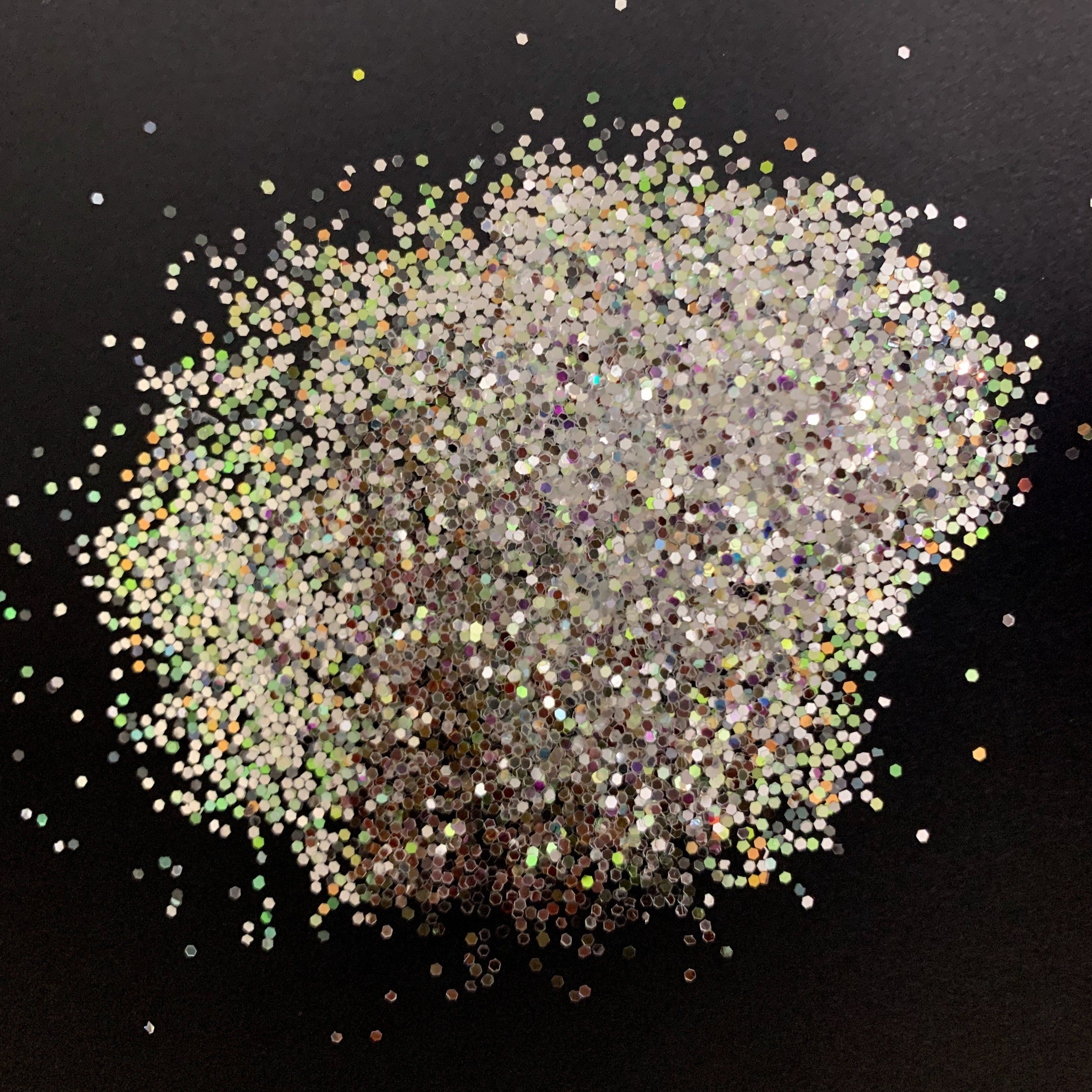A pile of silver medium glitter on a black surface.