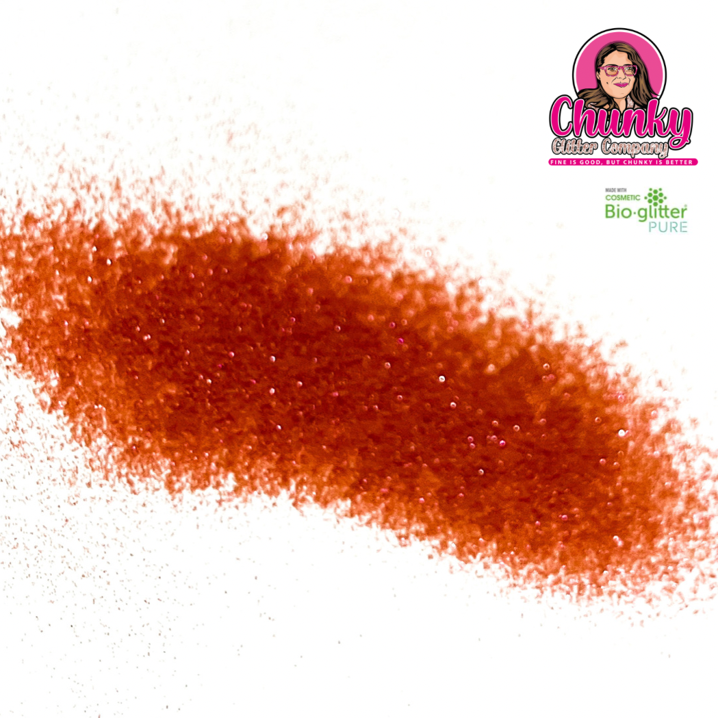 A pile of fuchsia iridescent biodegradable glitter on a white surface with a logo in the corner.