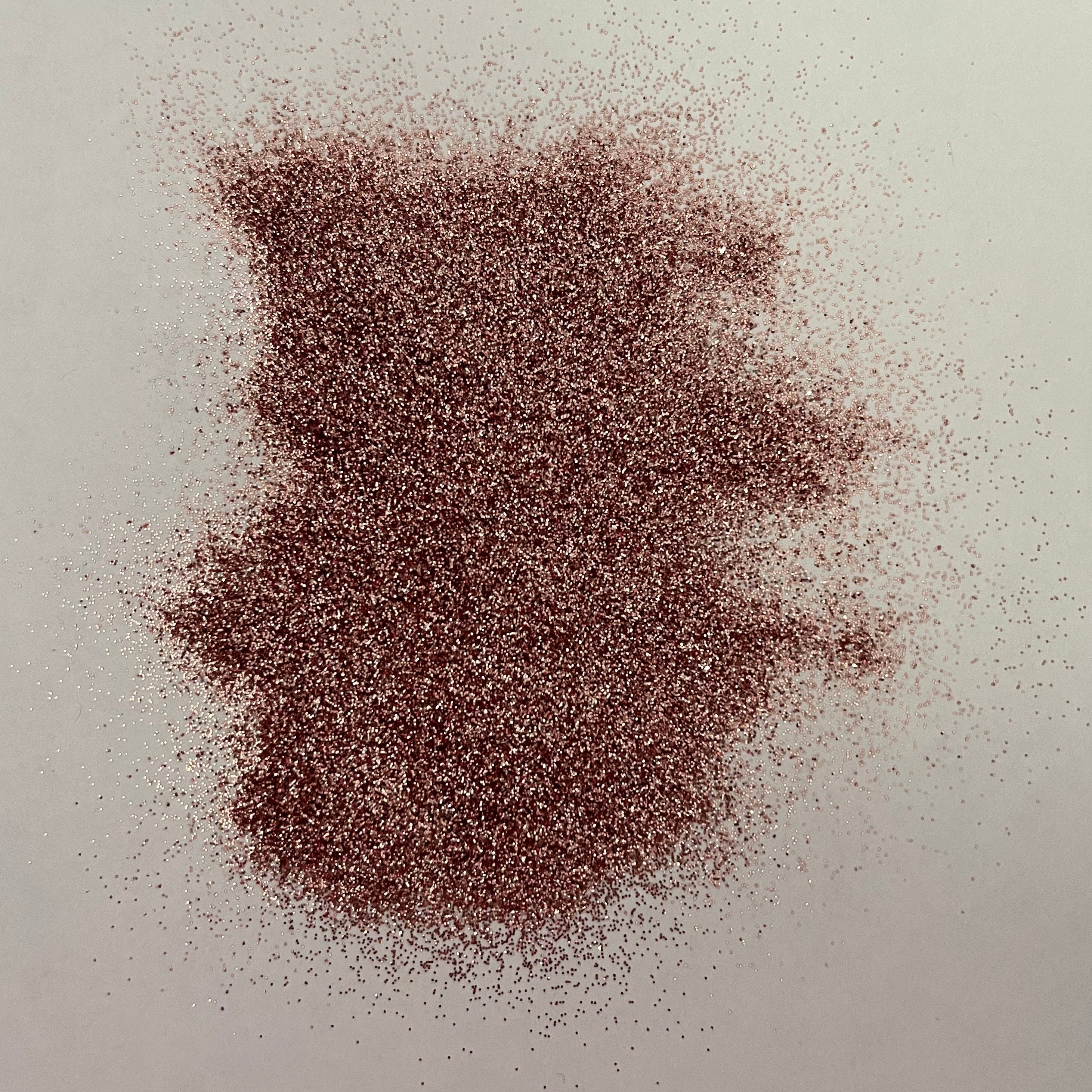 A pile of rose gold metallic glitter on a white background