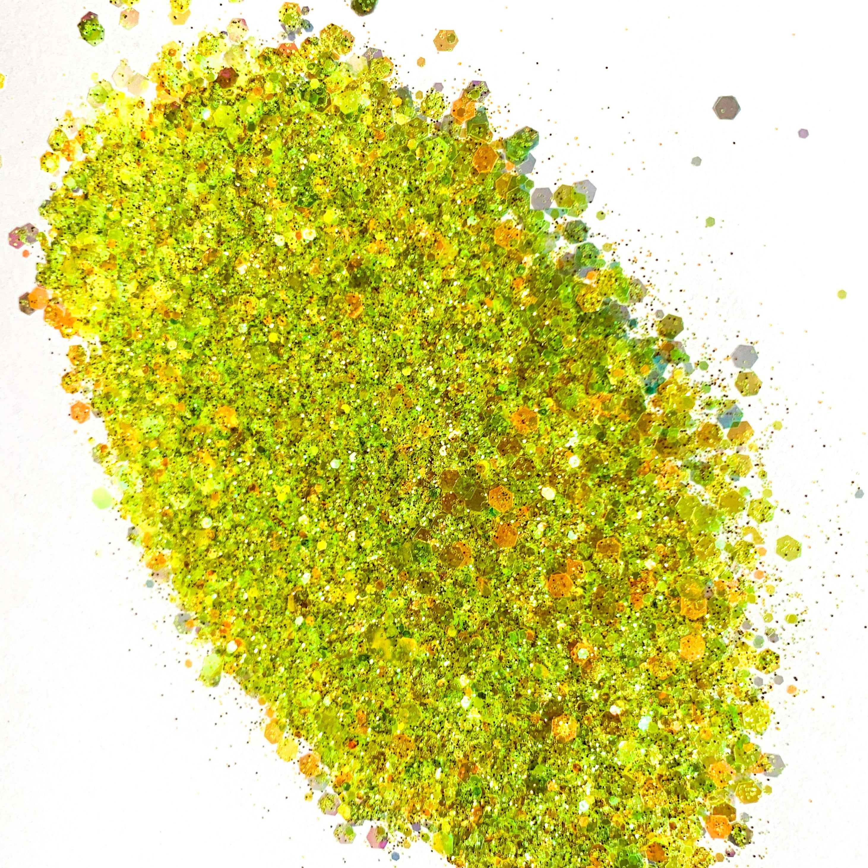 A close-up image of a yellow and green chunky mix glitter, showing the texture and the reflective surfaces of the glitter particles.