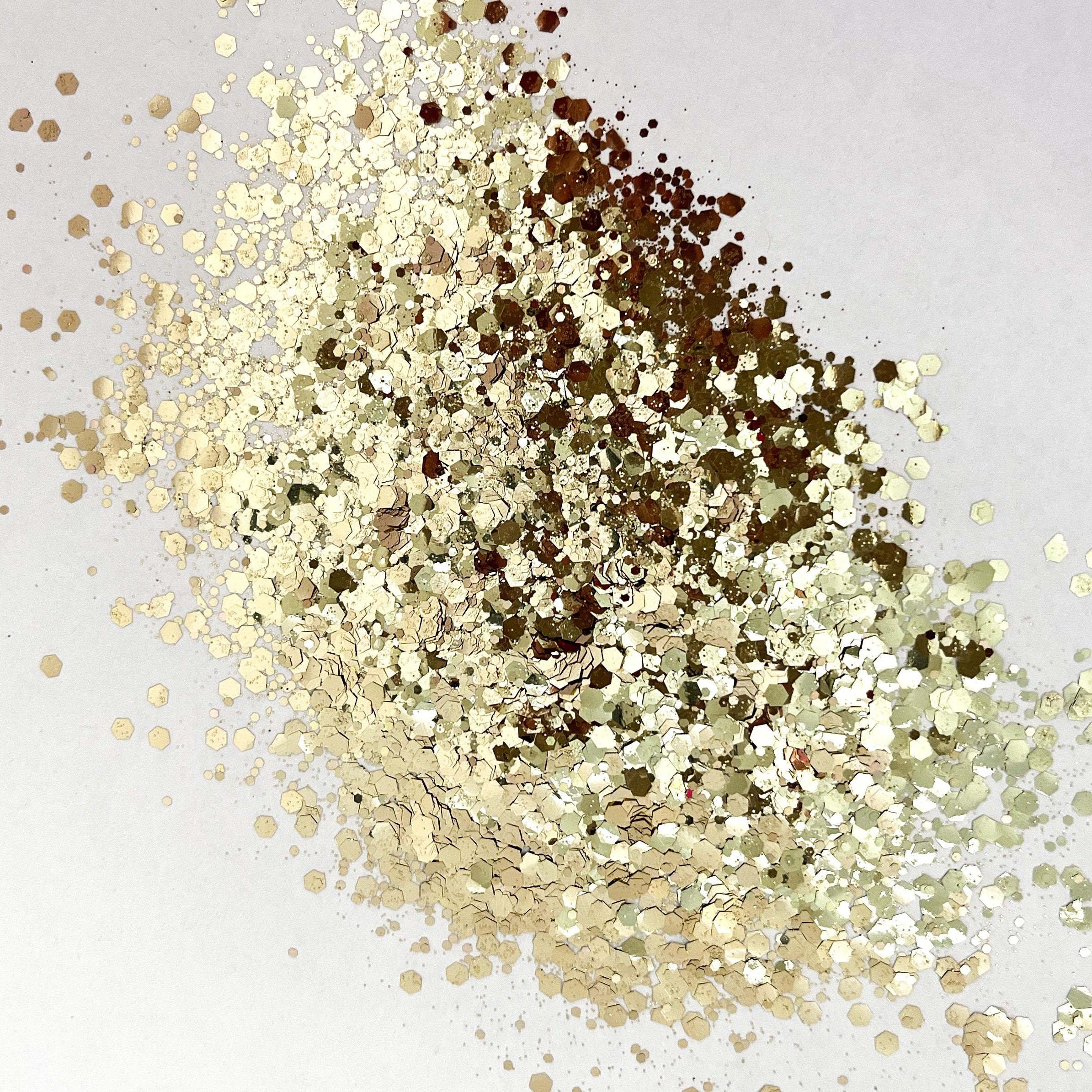 A pile of gold chunky glitter on a white background.