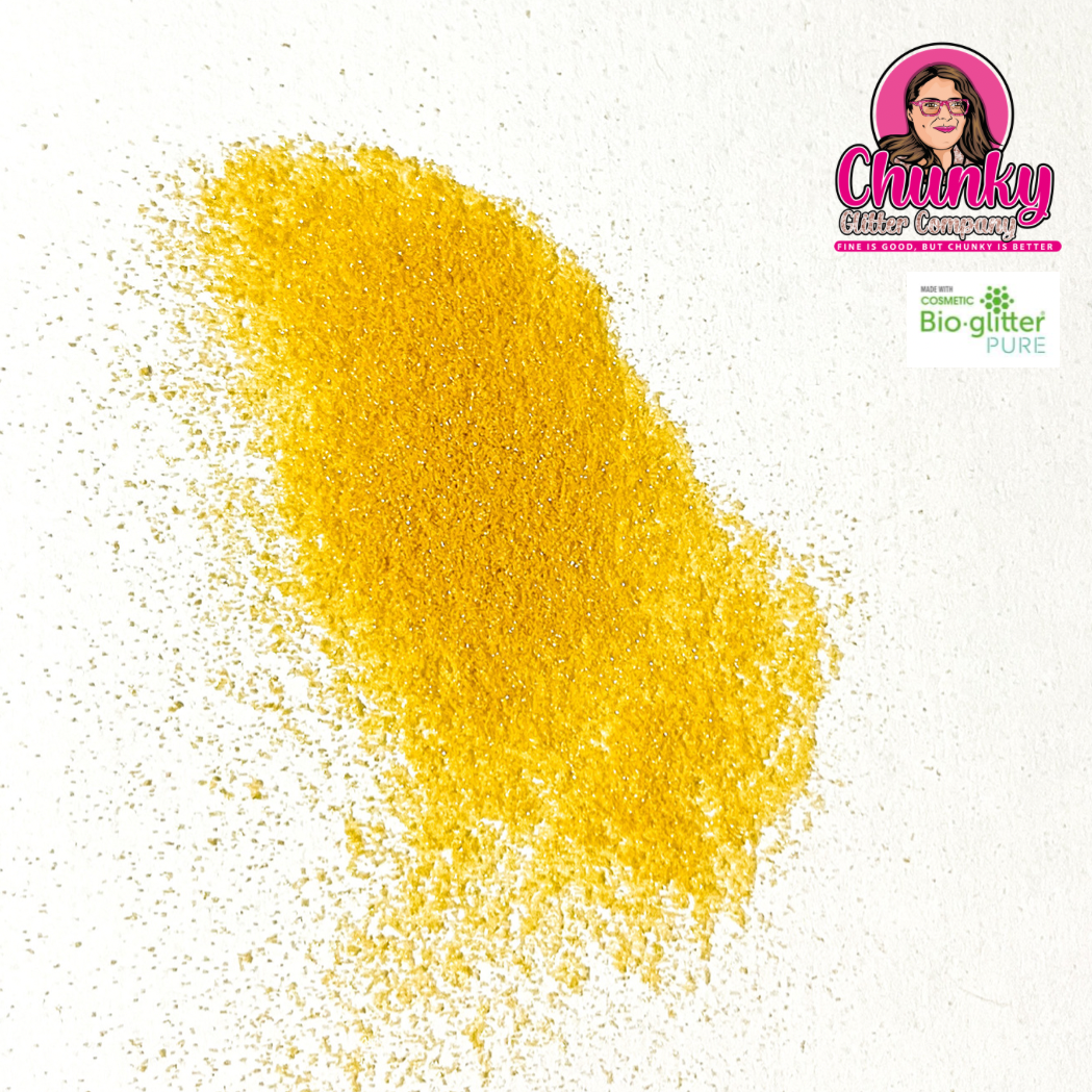 A pile of light gold iridescent biodegradable glitter on a white surface with a logo in the corner.