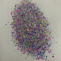A colorful mixture of various sizes of glitter particles, including pink, green, blue, and silver colors.