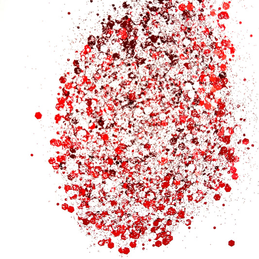 A close-up image of a red and white chunky mix glitter, displaying various sizes of particles against a white background.