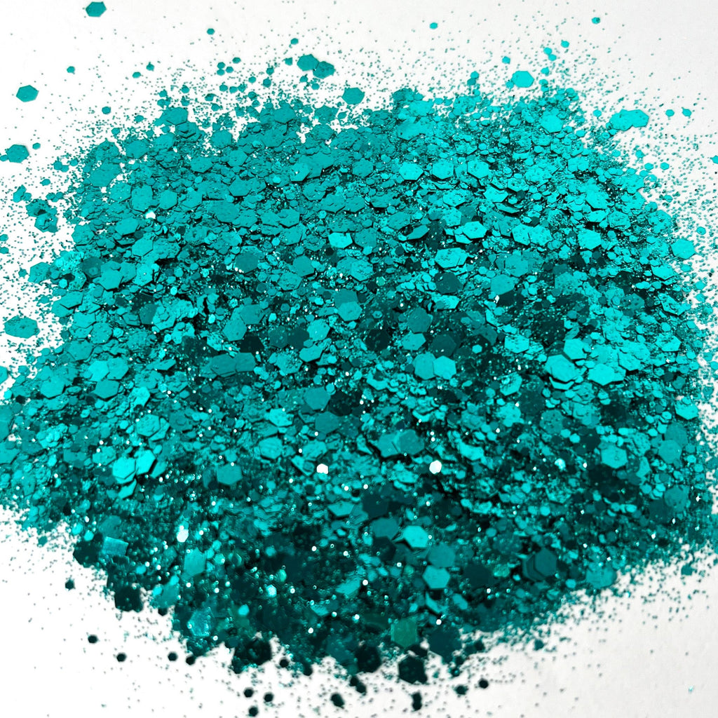 A pile of dark teal chunky glitter spread out on a white background.