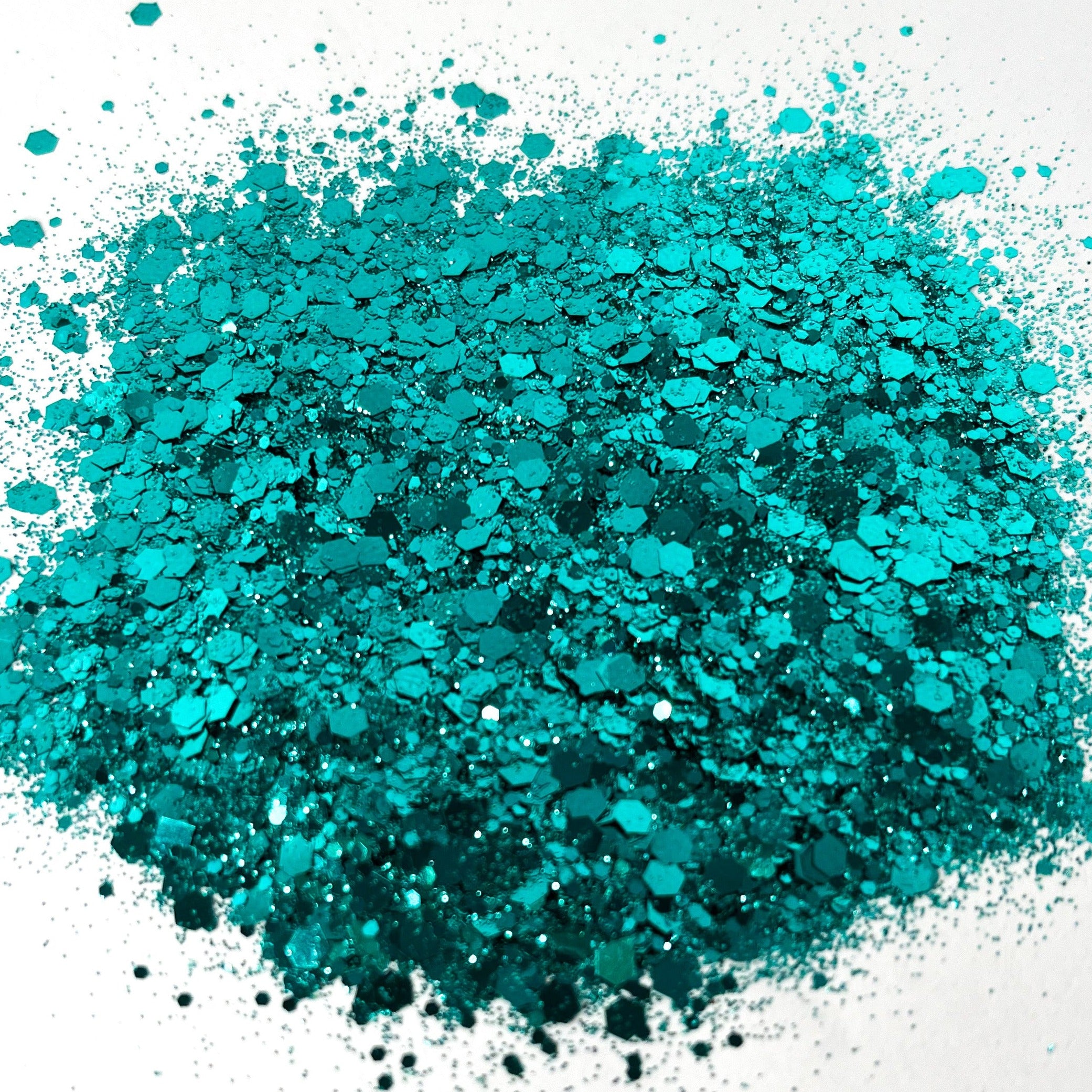 A pile of dark teal chunky glitter spread out on a white background.