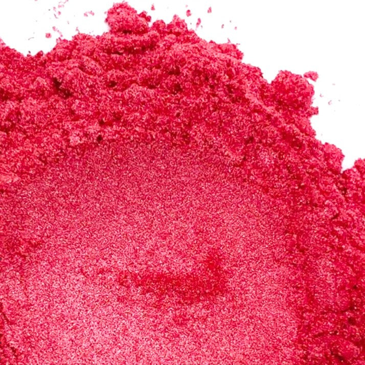 A pile of dark pink mica powder on a white background.